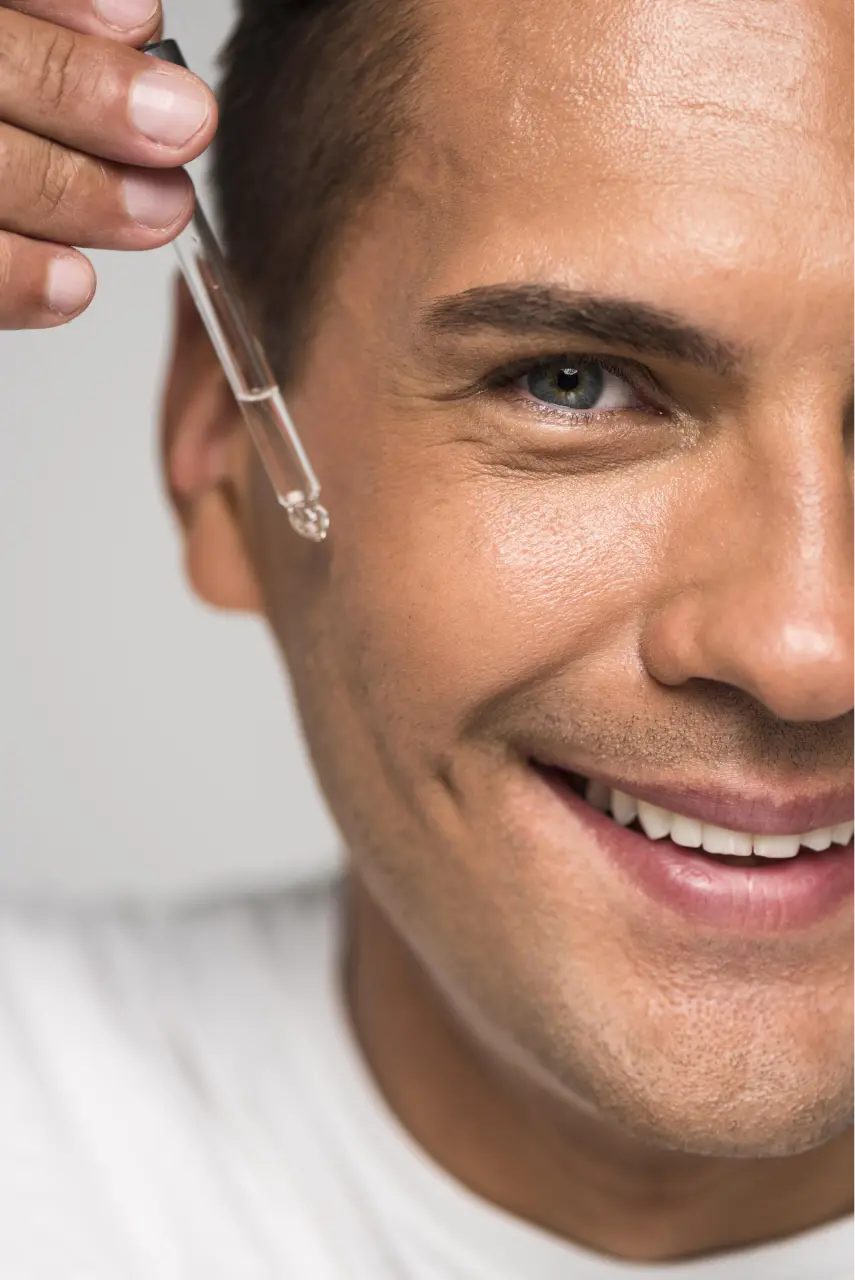 close-up-smiley-man-applying-serum
