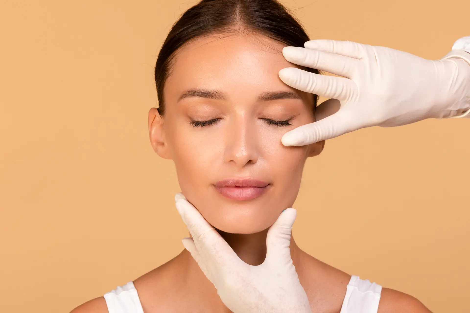 facial-treatment-cosmetologist-touching-beautiful-caucasian-woman-face-lady-sitting-beige-background (1)