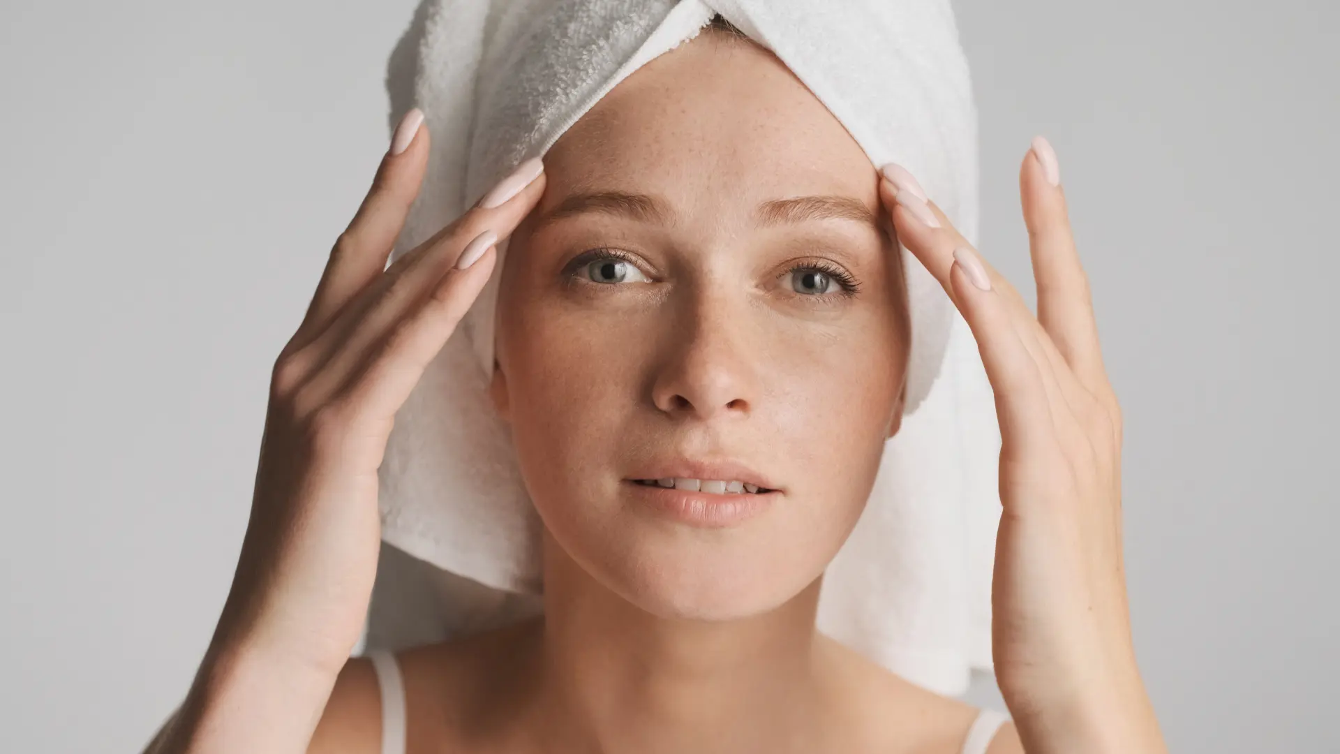 portrait-girl-with-towel-head-intently-looking-camera-white-background-beauty-concept