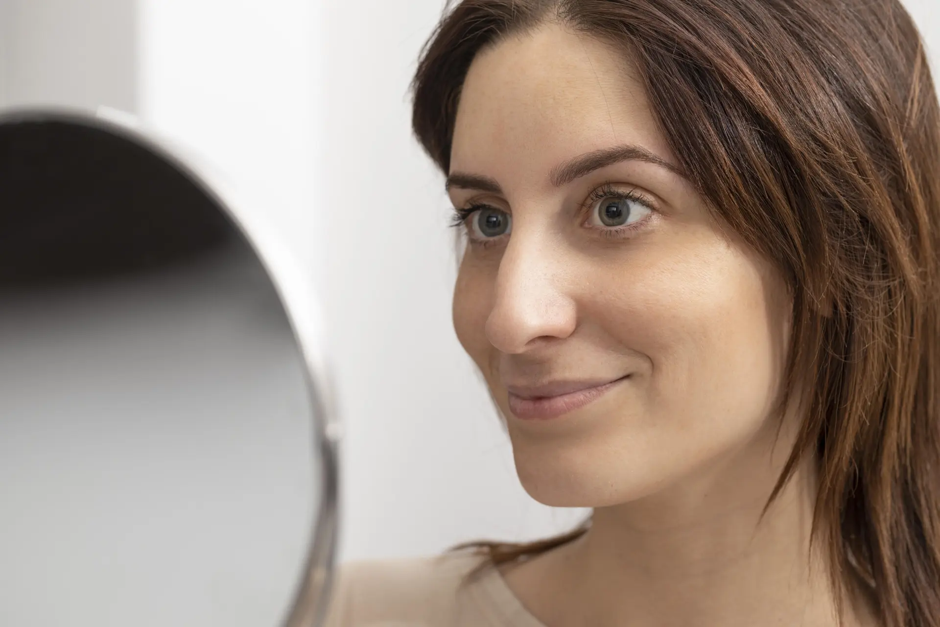 portrait-woman-looking-mirror-after-her-microblading-treatment