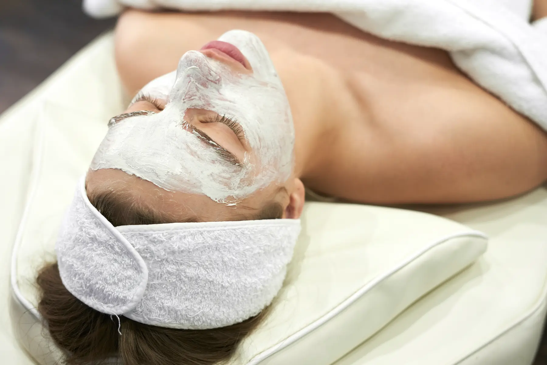 smiling-girl-beautician-young-woman-lies-couch-with-white-mask-spa-treatments-professional-facial-skin-care